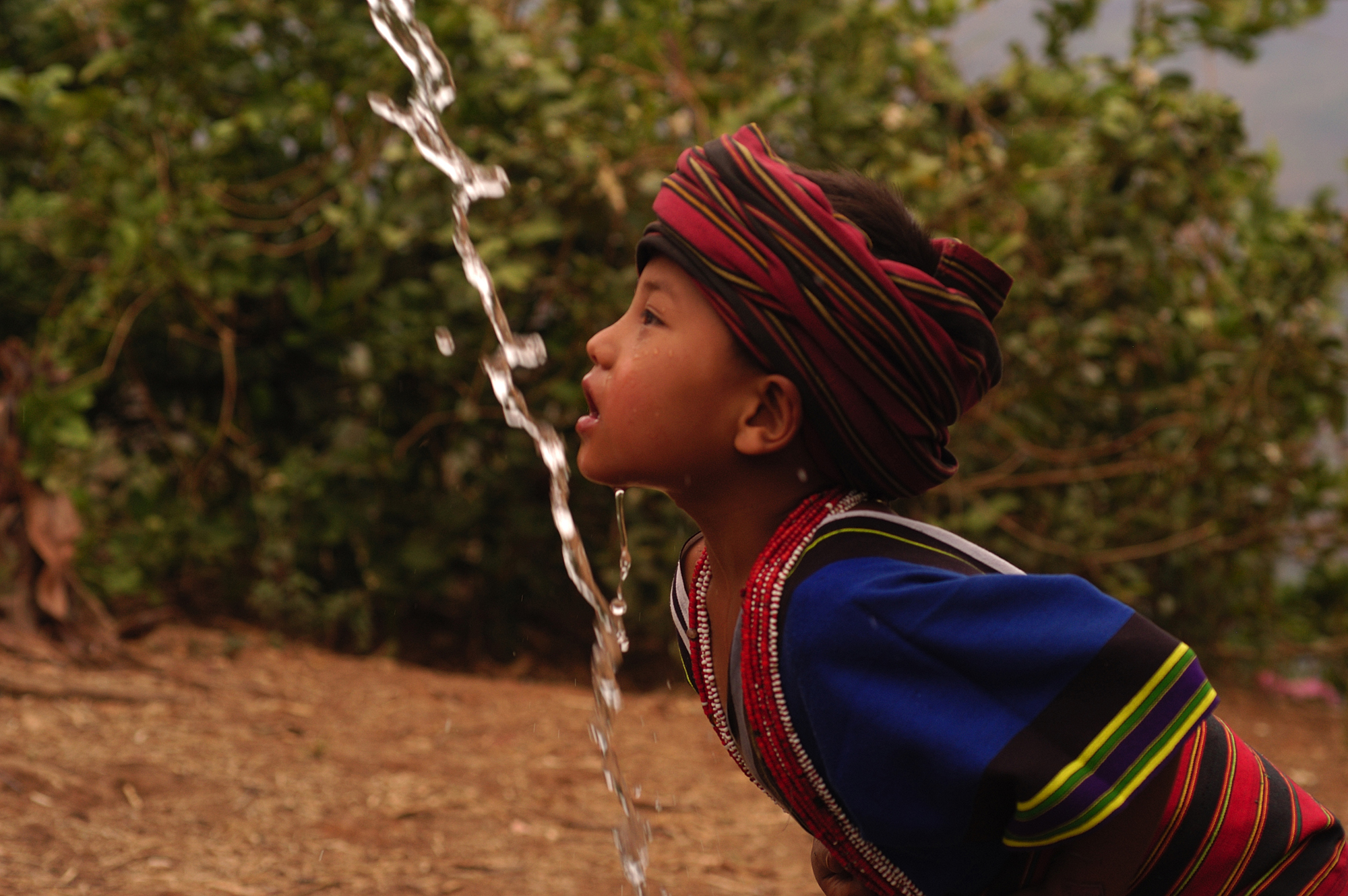 WHO_042154-2000px A young chin girl is drinking water under the water tap from gravity flow in Kan Thar Yone village in Southern Chin state in Myanmar