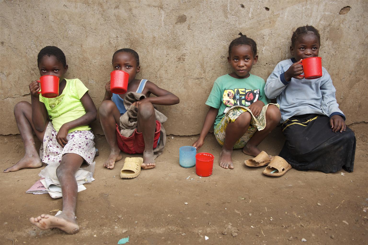 UNI127319 Children eat porridge that was just distributed, outside Shamba Primary School, in the Kakuma refugee camp, in the north-western Turkana District.