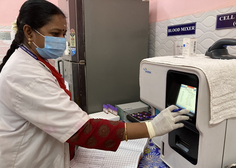 TB lab-Mythili fs A doctor wearing a mask and gloves using a machine